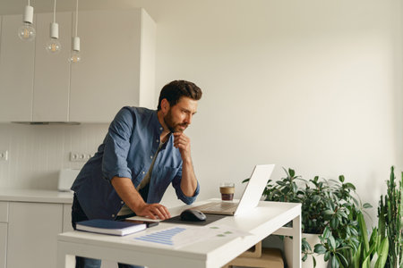 Male entrepreneur working on laptop on home kitchen. Distance work concept. High quality photoの写真素材