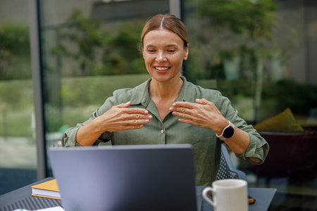 Businesswoman via videoconference discuss project with colleague use sign language sitting in cafeの写真素材