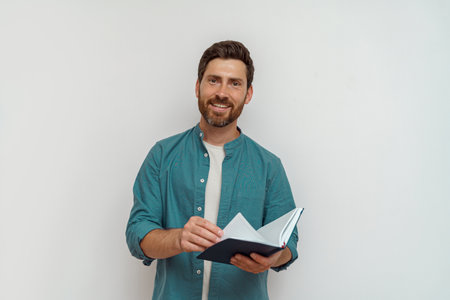 Focused male freelancer in casual clothes is leafing through his notepad on white background