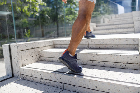 Close up legs and shoes of runner man running with sprint on the stairs in modern city
