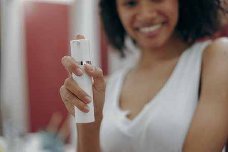 Close up of woman standing at bathroom and holding natural skincare or body care cosmetics bottleの写真素材