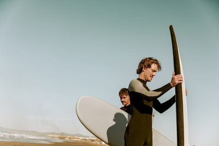 Group of friends surfers in wetsuits standing with surfboards and preparing for ride on wavesの写真素材