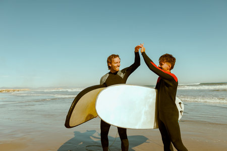 Two surfers greet each other by shaking hands before surfing on waves in oceanの写真素材