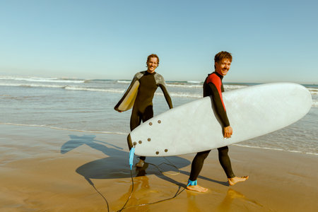 Group of smiling surfers with surfboards are walking on the beach after ride the wavesの写真素材
