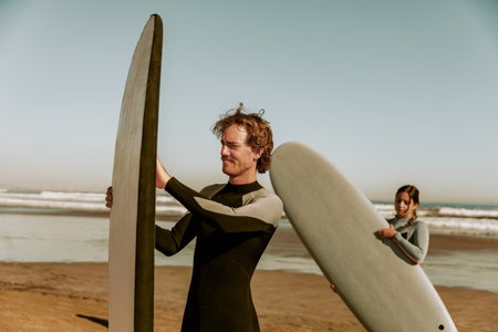 Surfers in wetsuits standing with surfboards and preparing for ride on wavesの写真素材