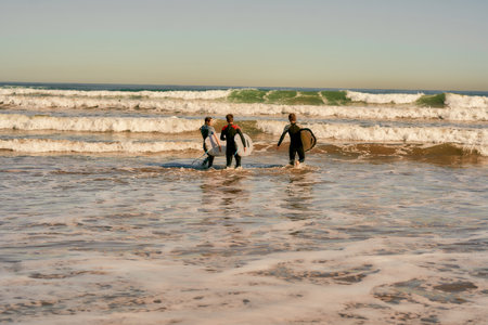 Group of friends with surfboards entering towards ocean for surfing on waves. High quality photoの写真素材