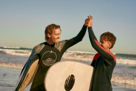 Two surfers greet each other by shaking hands before surfing on waves in ocean