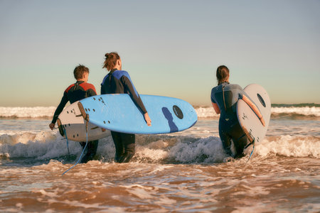 Group of surfers with surfboards in wetsuit entering towards ocean for ride the wavesの写真素材
