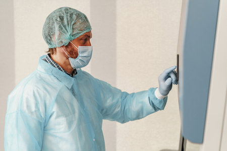 Male scientist in uniform and mask working in medical research laboratory use special equipment