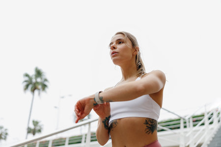 Active woman in sportswear looking on smartwatch after running. Outdoor sports in the morning