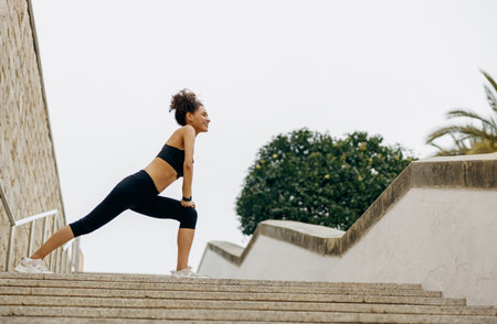 Young female athlete in tracksuit stretching outdoor and preparing to jogging. Healthy life concept
