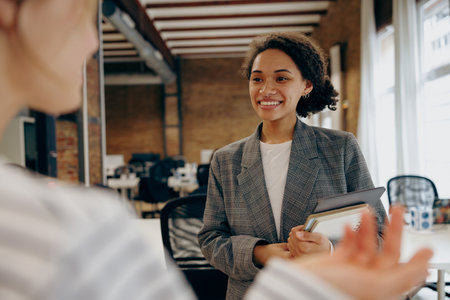 Two female managers met in the office interior and stopped to talking about meeting with clients