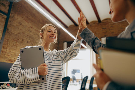 Successful business people giving each other a high five in a meeting
