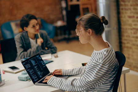 Female programmer enjoying time with laptop and distance job while sitting at coworking space