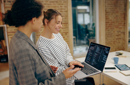 Female programmers enjoying time with laptop and distance job while standing at coworking spaceの写真素材
