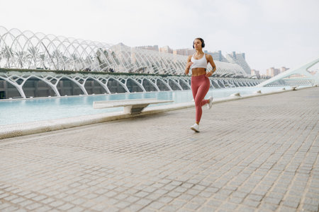 Active woman athlete is jogging on morning on modern building background. Healthy life conceptの写真素材