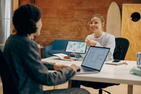 Happy business colleagues having discussion over tablet pc while sitting in coworking