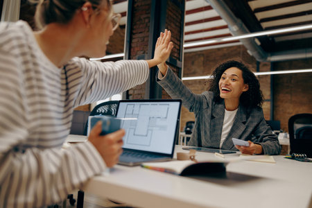 Successful business people giving each other a high five in a meeting. Corporate culture concept