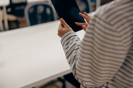 Close up of female freelancer is working on digital tablet standing on coworking backgroundの写真素材