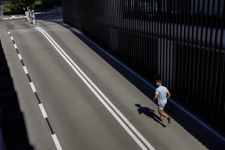 Muscular sport male sprinter in sportswear exercising sprint on city road. Healthy lifestyle concept