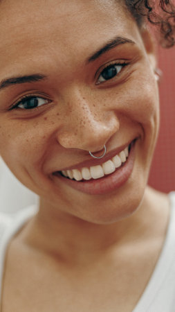 A Smiling Woman with Freckles and a Piercing Displayed in Beautiful Natural Lightの写真素材