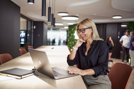 A Professional Woman Engaged in Work on Her Laptop Within a Contemporary Office Environmentの写真素材