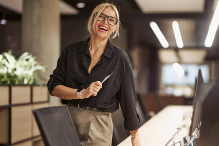 Cheerful Businesswoman in a Modern Office Environment with a Positive Atmosphere and Energyの写真素材