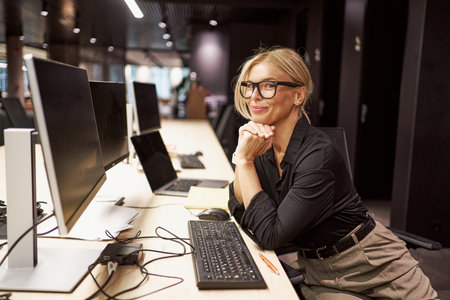 A Professional Woman Engaged in Her Work at a Modern Office with a Computer and Laptopの写真素材