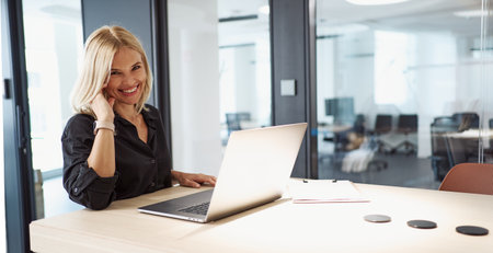 A Smiling Businesswoman Working Productively on Her Laptop in a Professional Office