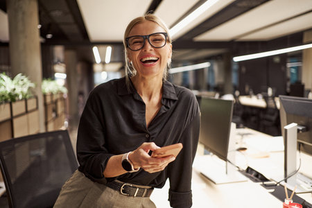 A Smiling Professional Woman Standing Confidently in a Modern Office Environment Spaceの写真素材