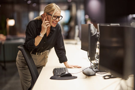 A Professional Woman Engaged on the Phone within a Modern Office Environment Settingの写真素材