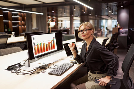 A successful businesswoman is thoroughly analyzing data within her modern office environmentの写真素材