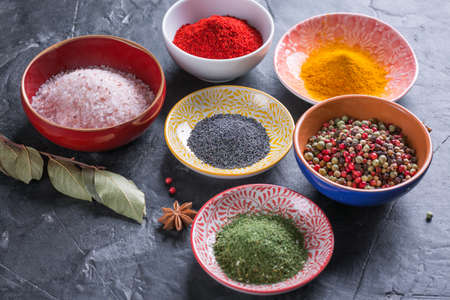 Various spices and seasonings on a dark stone backgroundの写真素材