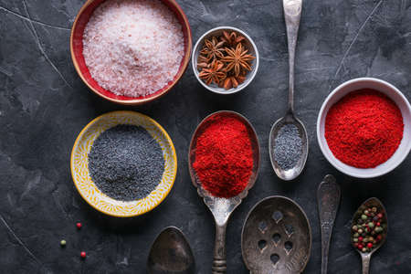 Various spices and seasonings on a dark stone backgroundの写真素材