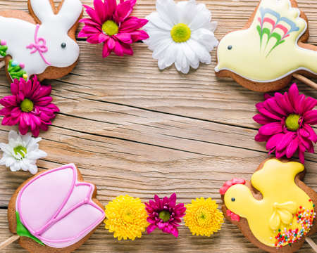 Food frame, Easter cookies on a wooden background, gingerbread in the shape of a rabbit, chicken, flower and birdの写真素材
