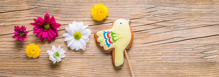 Easter gingerbread in the shape of a yellow bird on a wooden background, long bannerの写真素材