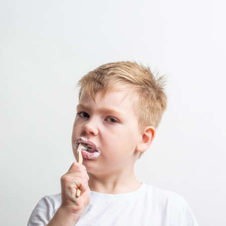 cute boy posing with bamboo toothbrush in his mouth, child brushes his teethの写真素材