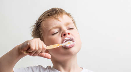 cute boy posing with bamboo toothbrush in his mouth, child brushes his teethの写真素材