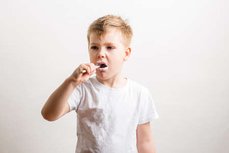 cute boy posing with bamboo toothbrush in his mouth, child brushes his teethの写真素材