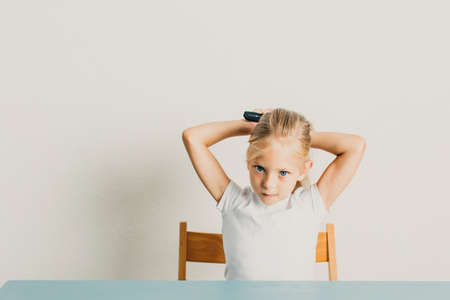 Beautiful little girl blonde combs her hairの写真素材