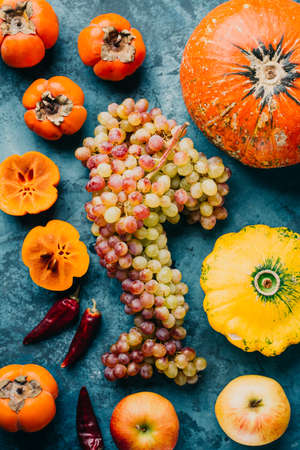 Autumnal fruits and vegetables. A bunch of grapes, pumpkin and persimmon on a blue background.