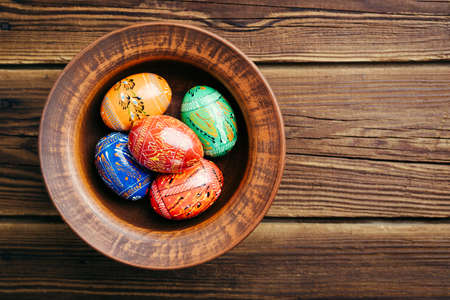 Easter eggs in a plate on a wooden background. Copy spaceの写真素材