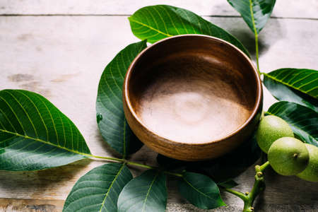 eco-friendly background. green leaves and a wooden bowl on the table.の写真素材