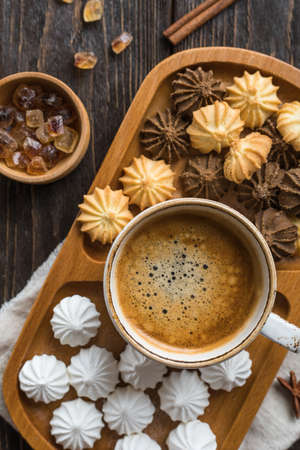 Mini meringue, cookies and coffee on a wooden tableの写真素材