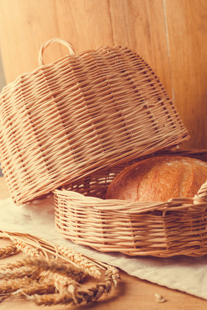 Basket of bread and wheat ears on the wooden background. vintage style.の写真素材