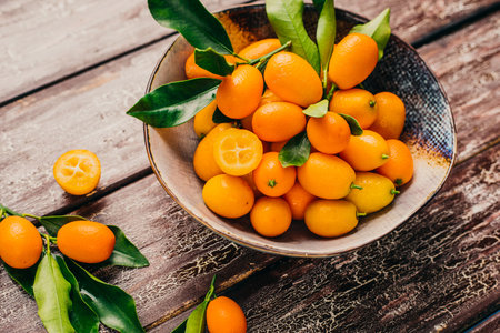 Cumquat or kumquat in a bowl on wooden backgroundの写真素材