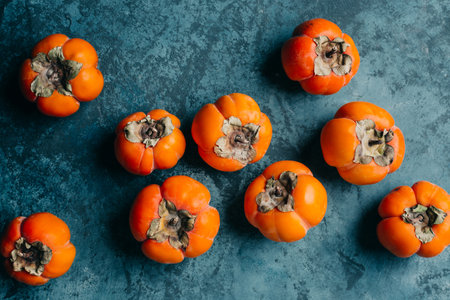 Ripe persimmon fruits on blue background. Top view.の写真素材