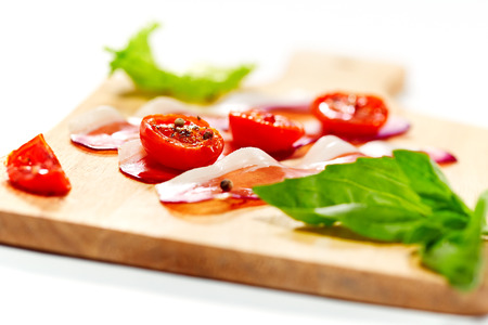 Dried cherry tomatoes with bacon served on carving board. Selective focus. の写真素材
