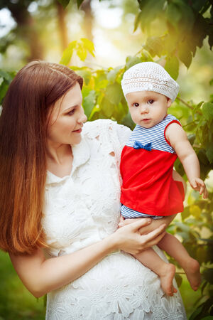 Beautiful young mother and baby daughter in summer park. Happy family. Trees, sunshine.の写真素材