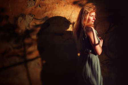 Art creative portrait of young woman near wall. Blonde hair. Sunset.の写真素材